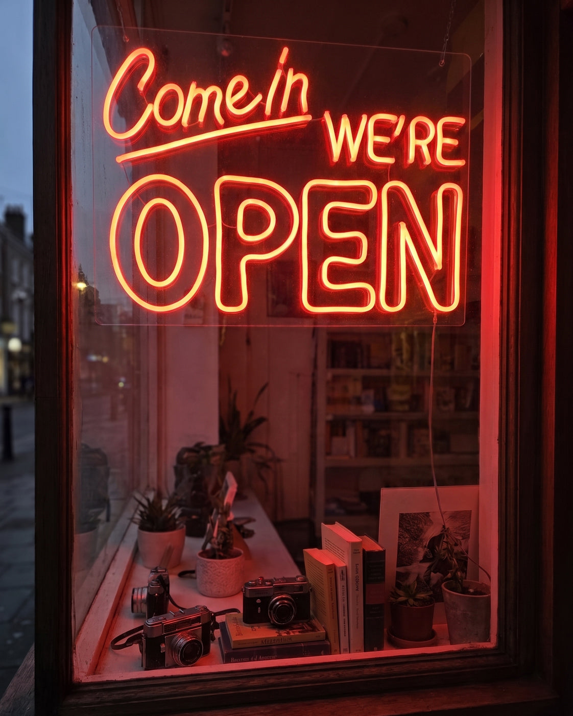 Liikkeen ikkunassa loistaa punainen Come in, we're open -neonkyltti.